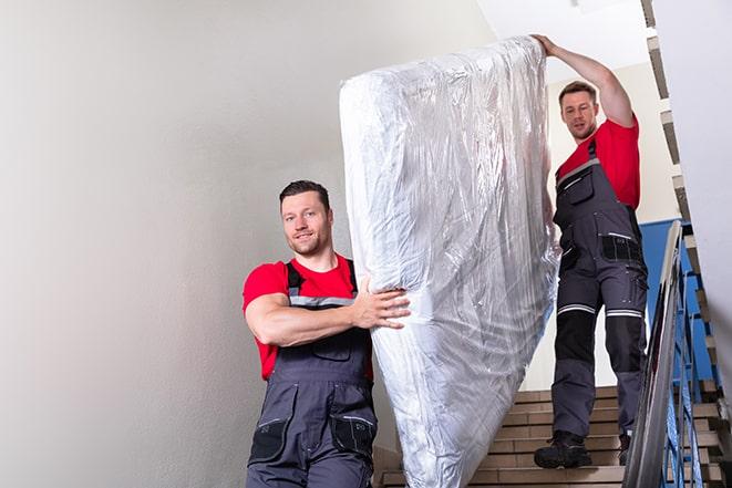 workers maneuvering a box spring through a narrow hallway in Cedarburg, WI